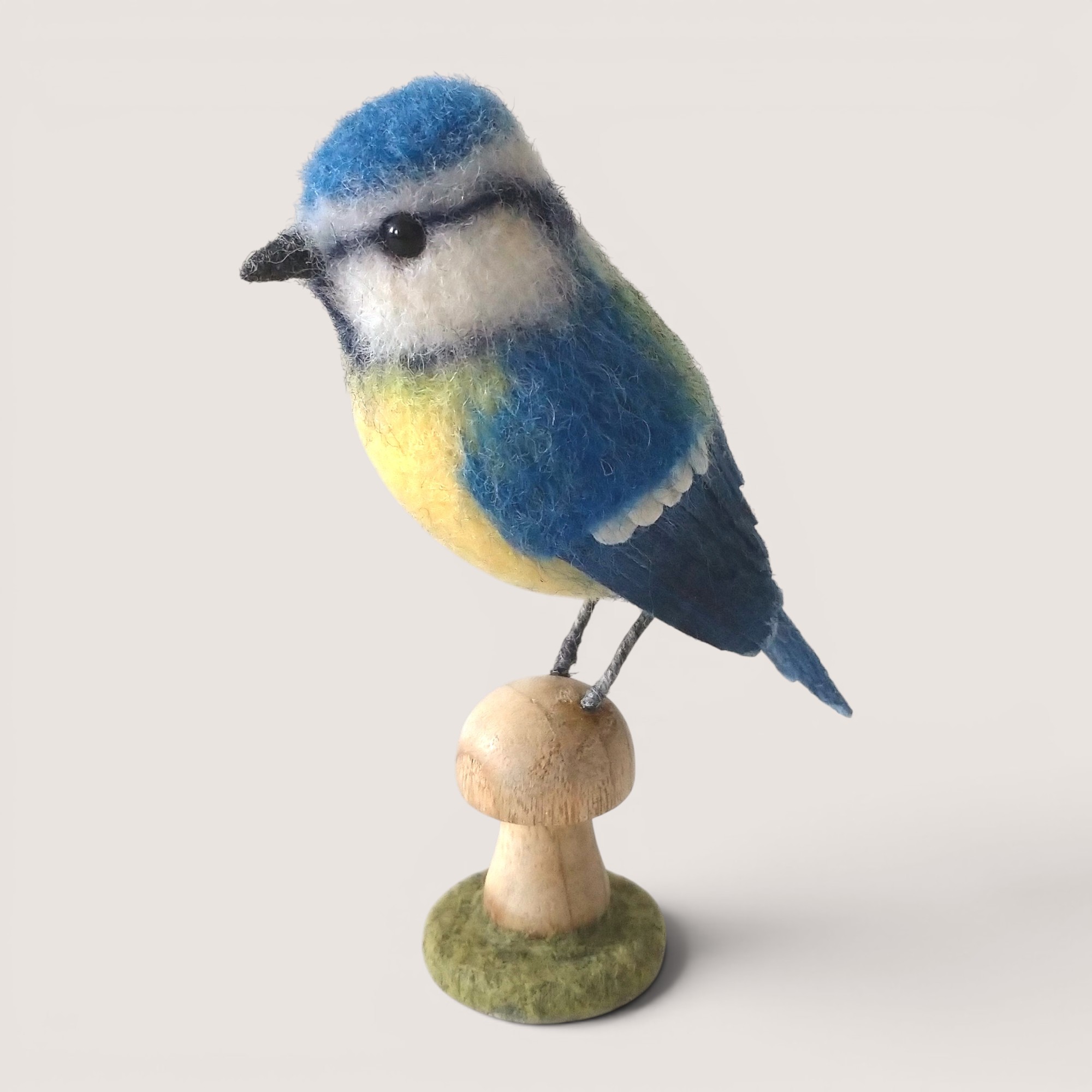 Blue Tit – Wooden Mushroom 1 Needle felted blue tit perched on a wooden mushroom with felt-covered woodland base by Grey Wren Studio.